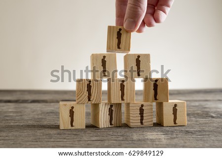 Man stacking a tower of wood blocks with human silhouettes, human resources and management concept.