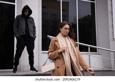 Man stalking young woman near building outdoors