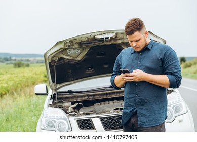 Man Stand In Front Of Broken Car With Phone. Broken In The Middle Of Nowhere