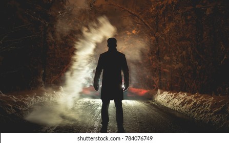 The Man Stand Near The Smoke On The Snowy Road. Evening Night Time