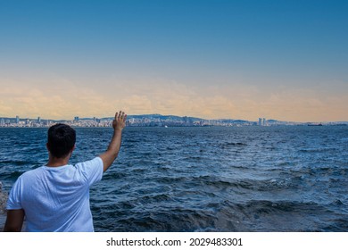 Man Standing Alone By The Sea.Lonely Young Man Waving.Missing Someone, Looking Away, It's Time To Say Goodbye.
