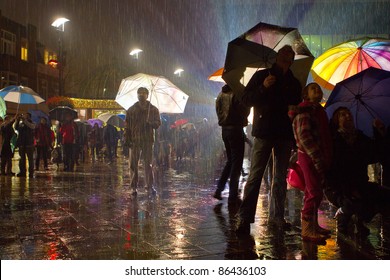 Man Standing Alone In A Crowd When It Is Raining With Enlightened Umbrellas.