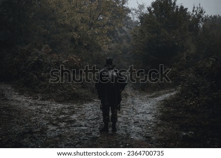 A man standing alone in the rainy forest with three paths in front of him moody autumn Greece