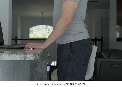 Man Standing With Anterior Pelvic Tilt Posture. This Man Has His Hands On A Table.