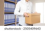 Man is standing in archive room. There stack of documents behind guy. Archivist at work. Lawyer carries box of documents. Cropped male works in archive. Storage and processing of accounting papers