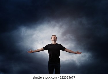 Man Standing With Arms Wide Open Over Dark Sky