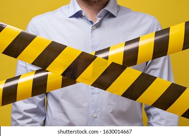 Man Standing Behind Black And Yellow Lines Of Barrier Tape That Forbids Passage. Concept Of No Entry. Protection From Coronavirus.