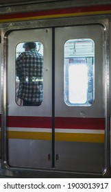A man is standing behind the commuter train door and the train is empty of passengers. Photo taken at Gambir Station, Jakarta, August 28, 2020.