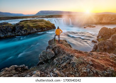 Man standing by amazing Godafoss waterfall in Iceland during sunset, Europe
