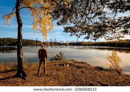 Man standing by forest lake looking at the view and enjoying time by himself 