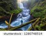 Man standing by a Koosah Falls, also known as Middle Falls, is second of the three major waterfalls of the McKenzie River, in the heart of the Willamette National Forest, in the U.S. state of Oregon. 