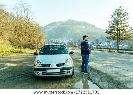 Man standing by the road with automobile