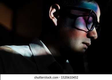 A man standing in the dark room with the light shading his face.