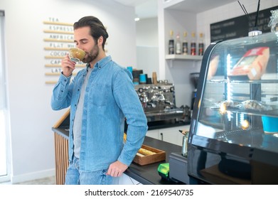 Man standing drinking coffee with closed eyes