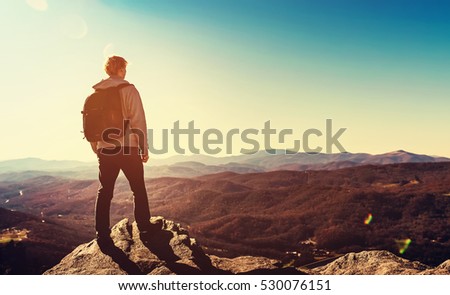 Man standing at the edge of a cliff overlooking the mountains below