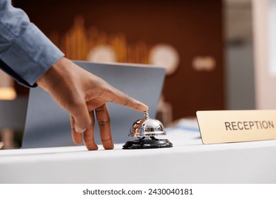 Man standing at empty reception desk, using service call bell to get attention of hotel employees, close up. Travel accommodation, customer service in hospitality industry concept - Powered by Shutterstock