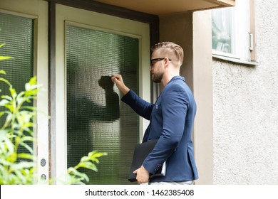 Man Standing At The Entrance Of The House Knocking The Door