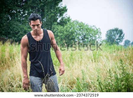 A man standing in a field of tall grass, during an adventurous trip, maybe he's lost 
