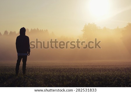 Man standing in the fog at sunrise