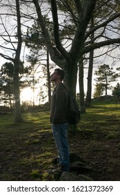 man standing in the forest with sun rays at sunset