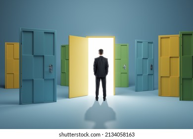 Man standing in front of abstract colorful puzzle door in interior. Future, choice, success, direction, opportunity and solution concept - Shutterstock ID 2134058163