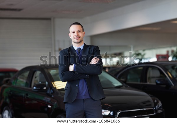 Man standing\
in front of a car in a\
dealership