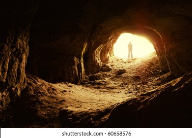 man standing in front of a cave entrance