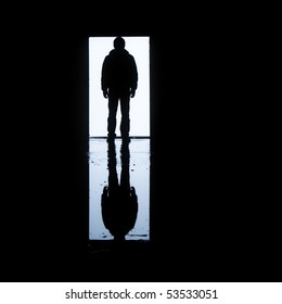 A man standing in front of a door with his image reflected on water