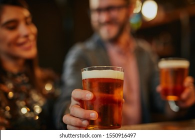 Man Standing In Group And Giving Beer To A Friend. Irish Pub Interior. Nightlife.