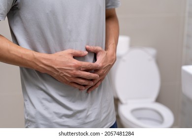 Un hombre de pie tiene diarrea y comida severamente tóxica. El hombre toca el vientre en el baño. Dolor abdominal, diarrea, concepto de cáncer de colon 