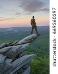 Man standing high on tip of rock at Rough Ridge Overlook on Grandfather Mountain in North Carolina.