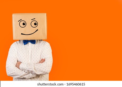 Man standing with his head in a box and suspicious gesture drawn on it and on a orange background. Front view. Copy space - Shutterstock ID 1695460615