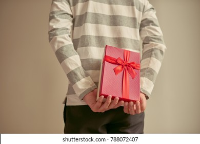 Man Standing And Holding Red Gift Box Behind His Back