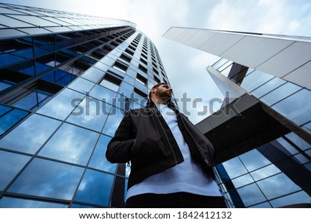 Man standing infrong of big business building looking infront of it.
