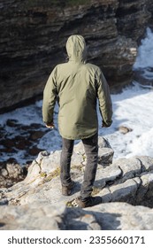 Man standing looking down at the ocean view from a cliff