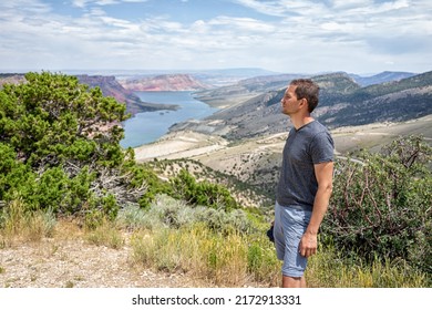 Man standing looking at view over Sheep Creek Overlook in Manila, Utah near Flaming Gorge National Park with cloudy valley and river