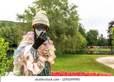 A man standing in mask and masquerade costume agains the park background