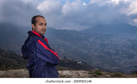 man standing at mountain top with dramatic sky at evening