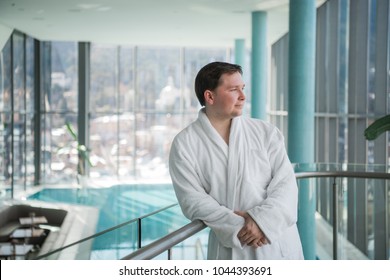 Man standing next to a pool in a robe and relaxing - Powered by Shutterstock