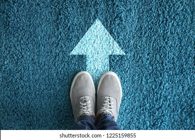 Man Standing On Carpet With Arrow Pointing In One Direction. Concept Of Choice