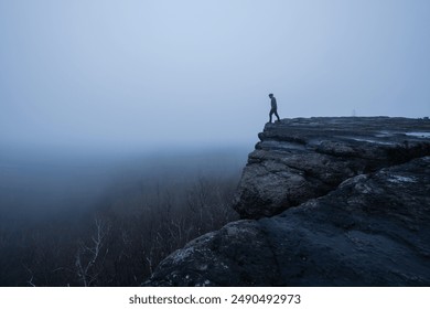 A man standing on the edge in the gloomy and totally moody view deep in the foggy rocks with the best dark and mystic atmosphere in the north of Bohemia. - Powered by Shutterstock