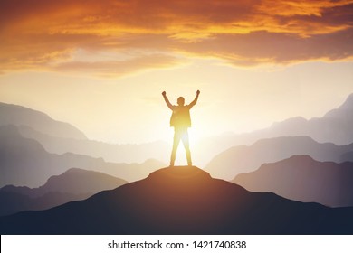 Man standing on edge of mountain feeling victorious with arms up in the air. Success, life goals, achievement concept.