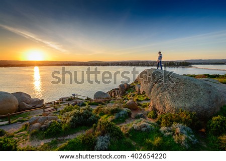 Man standing on the edge of the rock at sunset. View from Granite Island, South Australia