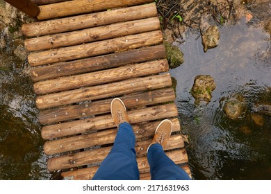 Man standing on a modern wooden bridge (boardwalk, walkway). Blue jeans, brown boots. River in a forest park. Spring, early summer. Nature, tourism, hiking, nordic walking, healthy lifestyle - Powered by Shutterstock