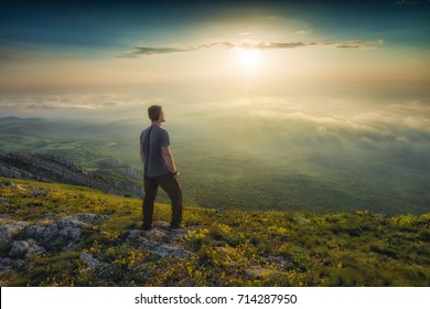 Man standing on a mountain hill and contemplate the sunset above Crimea mountains.