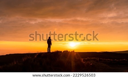 A man standing on a mountain as the sun sets. Panoramic photo, sunset silhouette