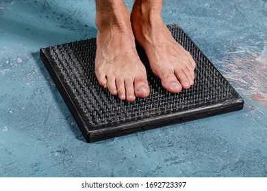 Man Standing On Natural Foot Wooden Massager With Hobnails, Spikes That Helps Blood Circulation. Recommended By Natural Way Of Distressing.
