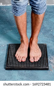 Man Standing On Natural Foot Wooden Massager With Hobnails, Spikes That Helps Blood Circulation. Recommended By Natural Way Of Distressing.
