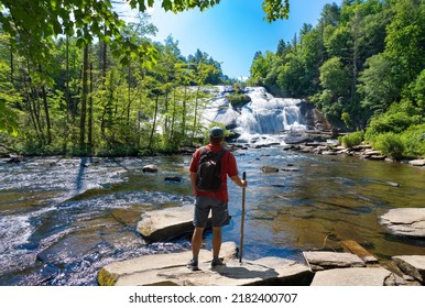 Man Standing On The Rock Enjoying Beautiful Waterfall View. High Falls  Of Dupont State Forest In Brevard. Blue Ridge Mountains, Near Asheville, Western North Carolina, USA.