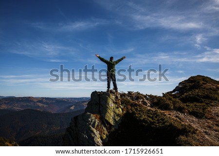 Man standing on rock. Hands up. Freedom concept. Sky copy space.